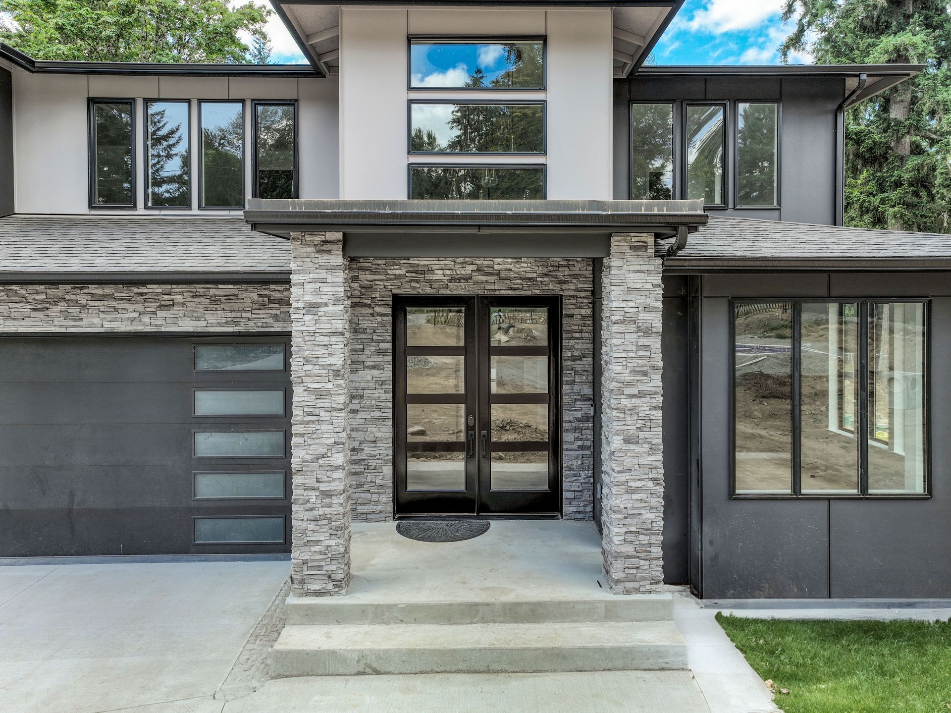 A modern house with a stone facade and a gray garage door.
