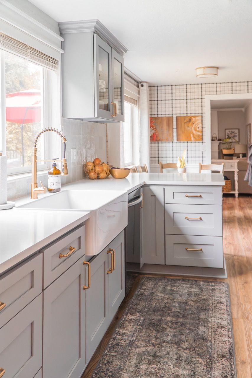 A kitchen with white cabinets , a sink , and a rug.