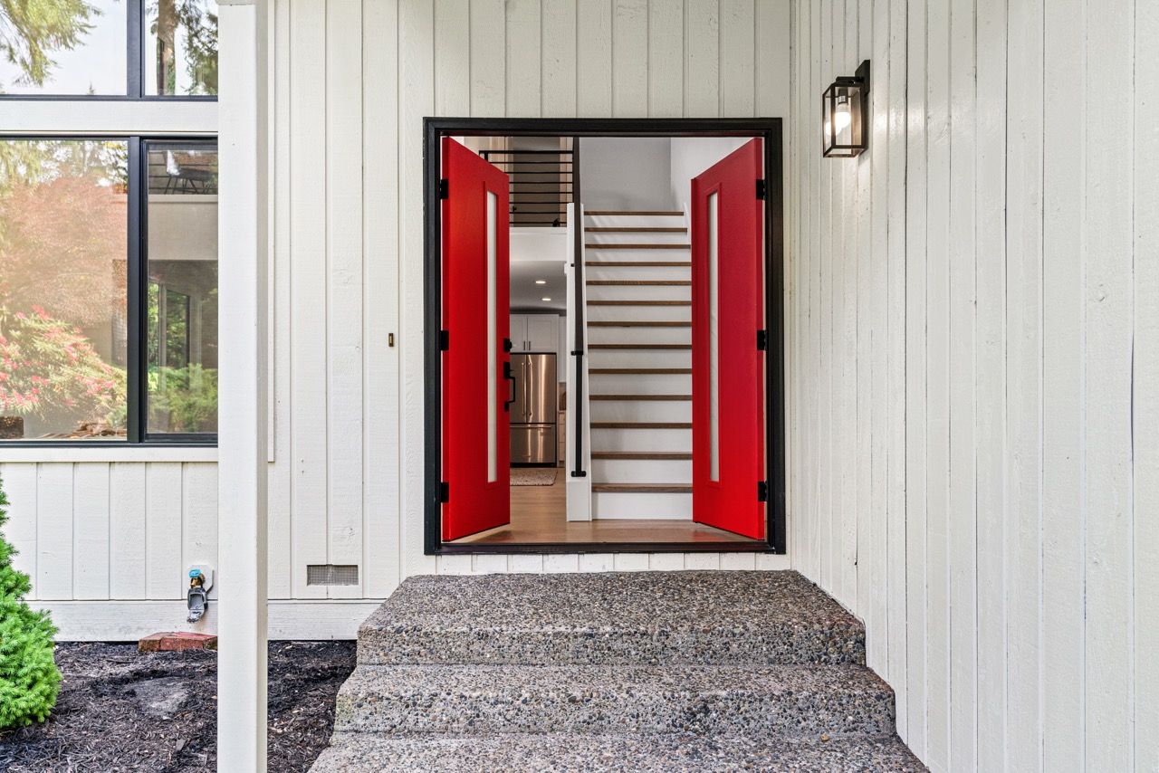 A white house with red doors and stairs.