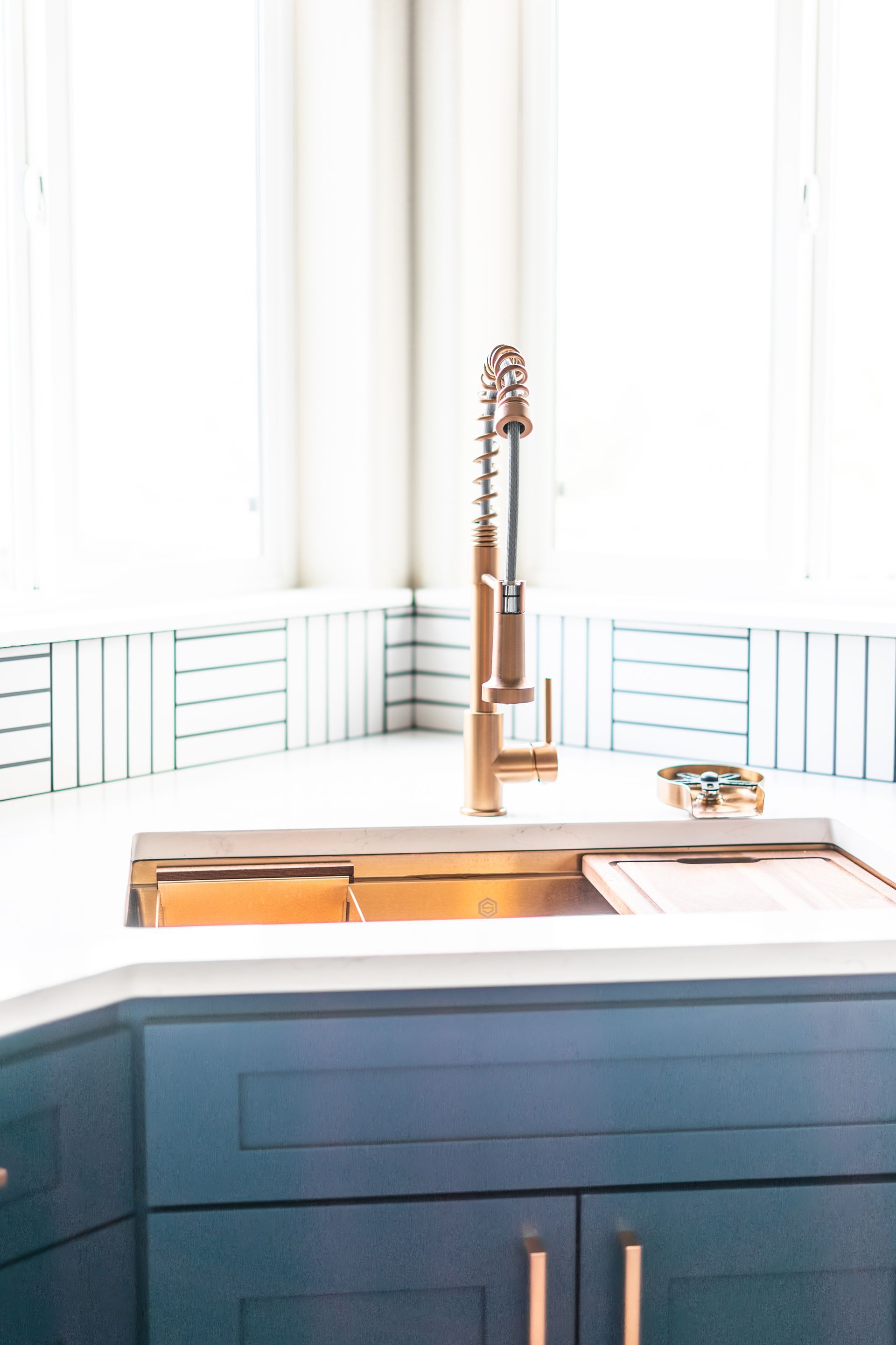 A kitchen sink with a copper faucet and blue cabinets.