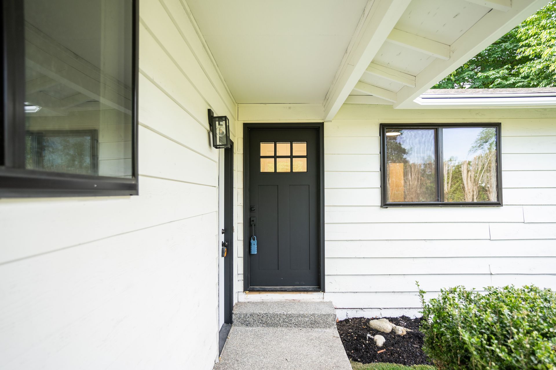 The front door of a white house with a black door and windows.