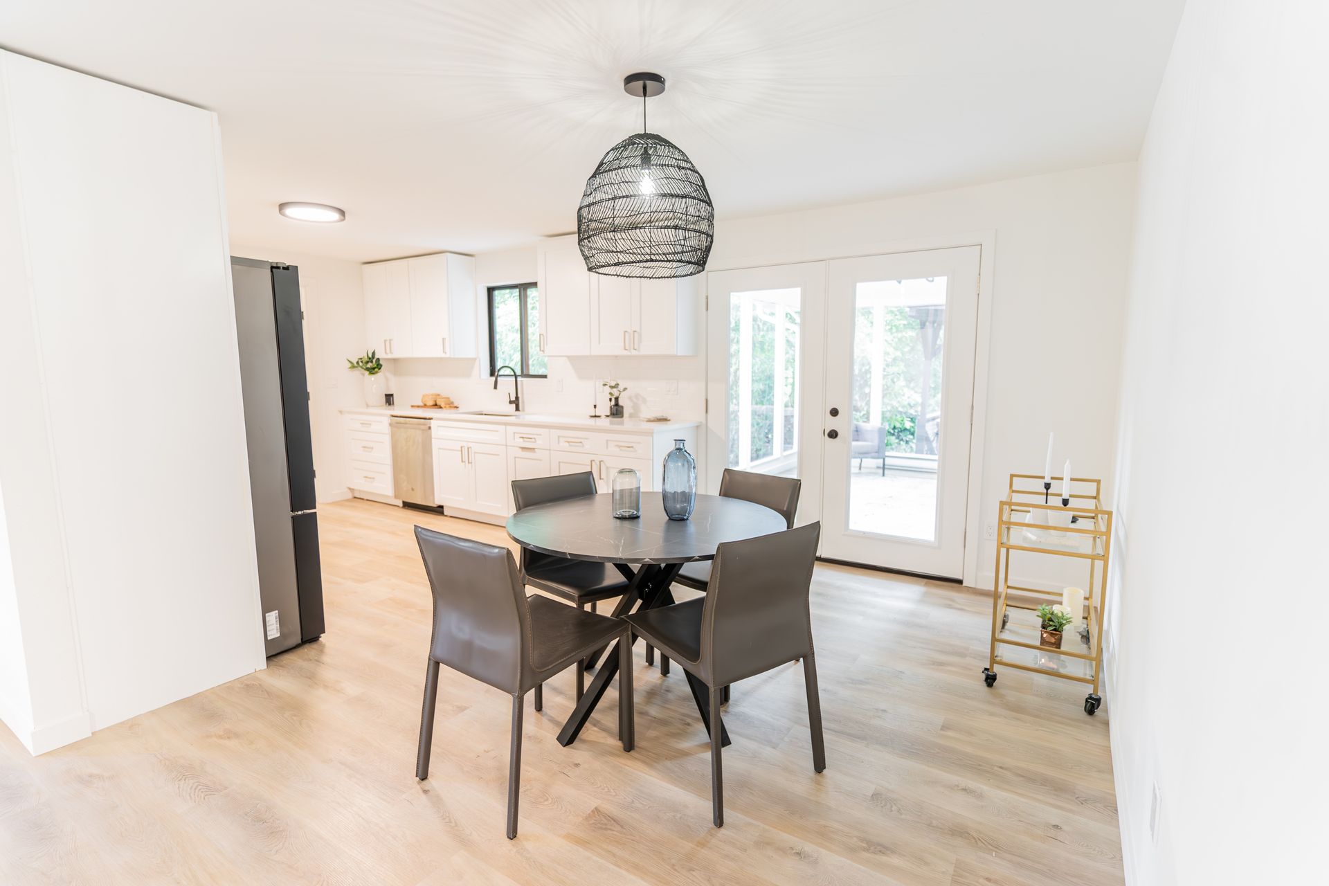 A dining room with a round table and chairs and a bar cart.