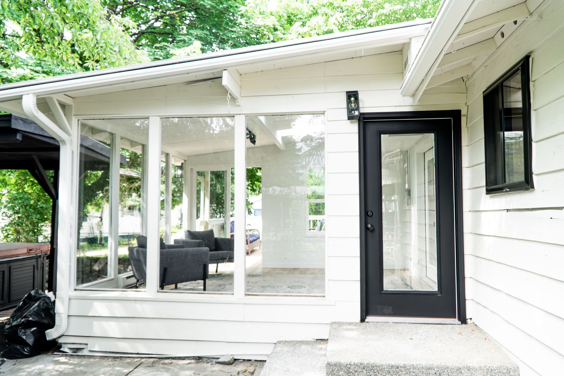 A white house with a screened in porch and a black door.