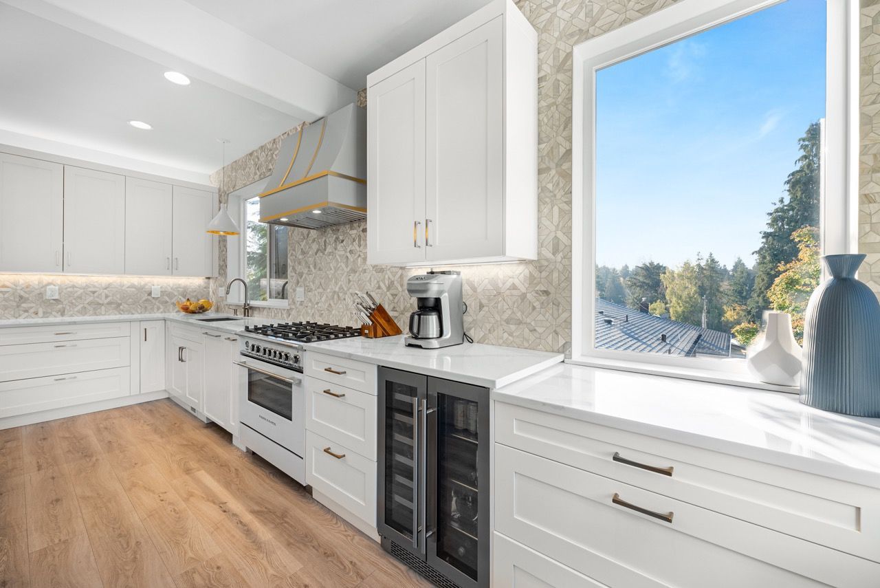 A kitchen with white cabinets , a stove , a refrigerator and a window.