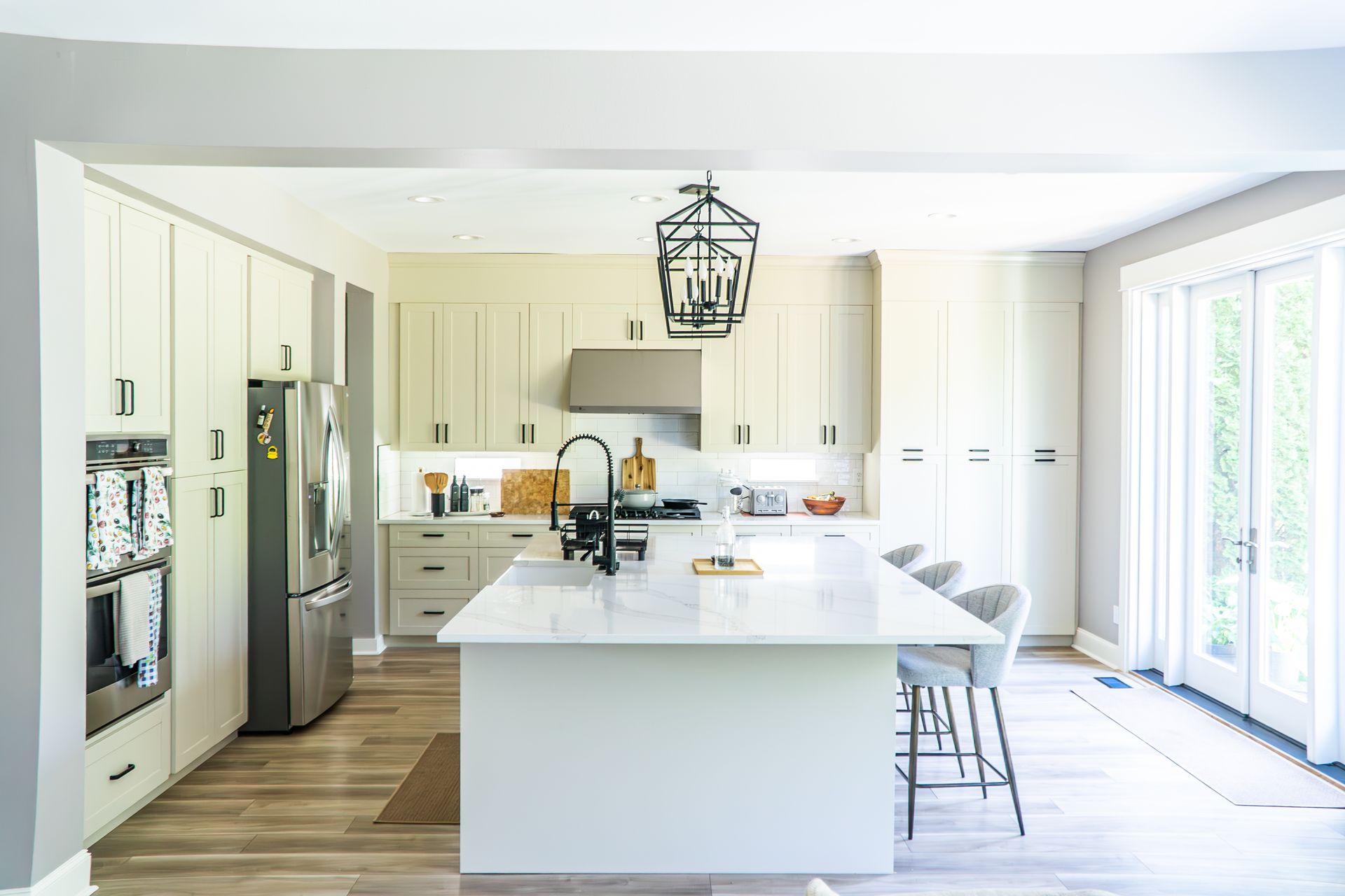 A kitchen with white cabinets , stainless steel appliances , and a large island.