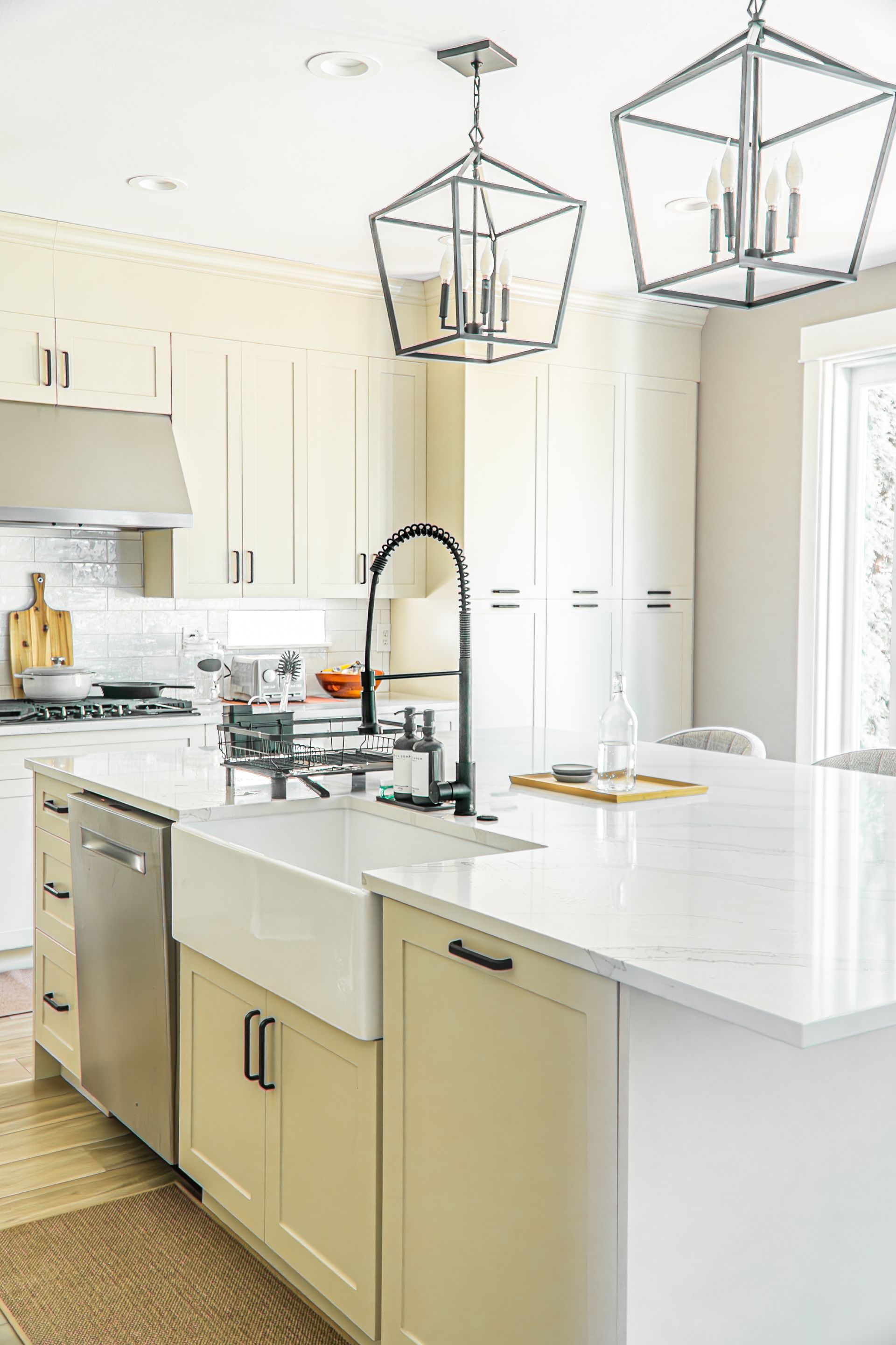 A kitchen with white cabinets , a white sink , a stainless steel dishwasher , and a large island.