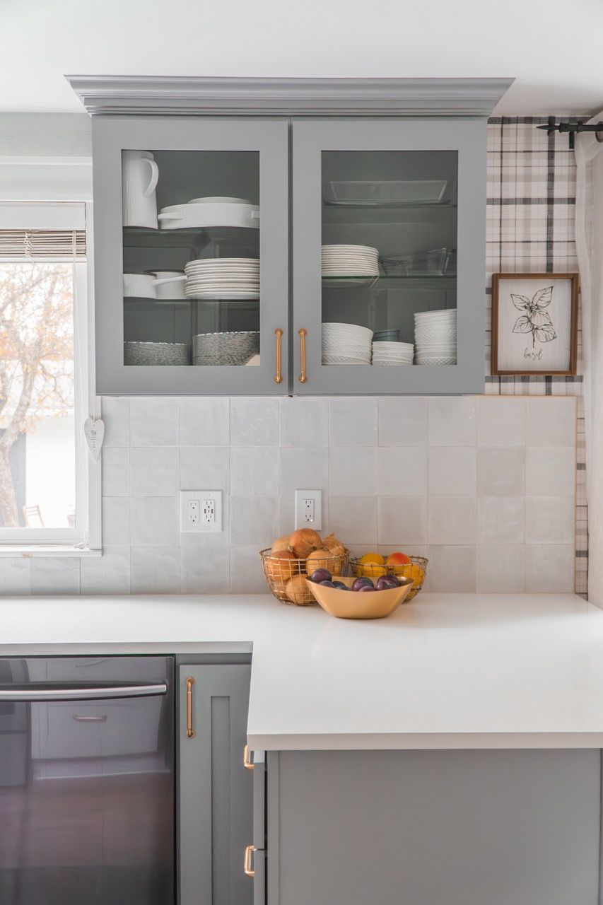 A kitchen with gray cabinets and a bowl of fruit on the counter.