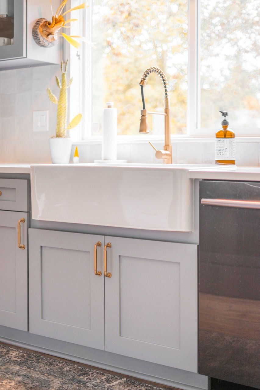 A kitchen with a sink , dishwasher , cabinets and a window.