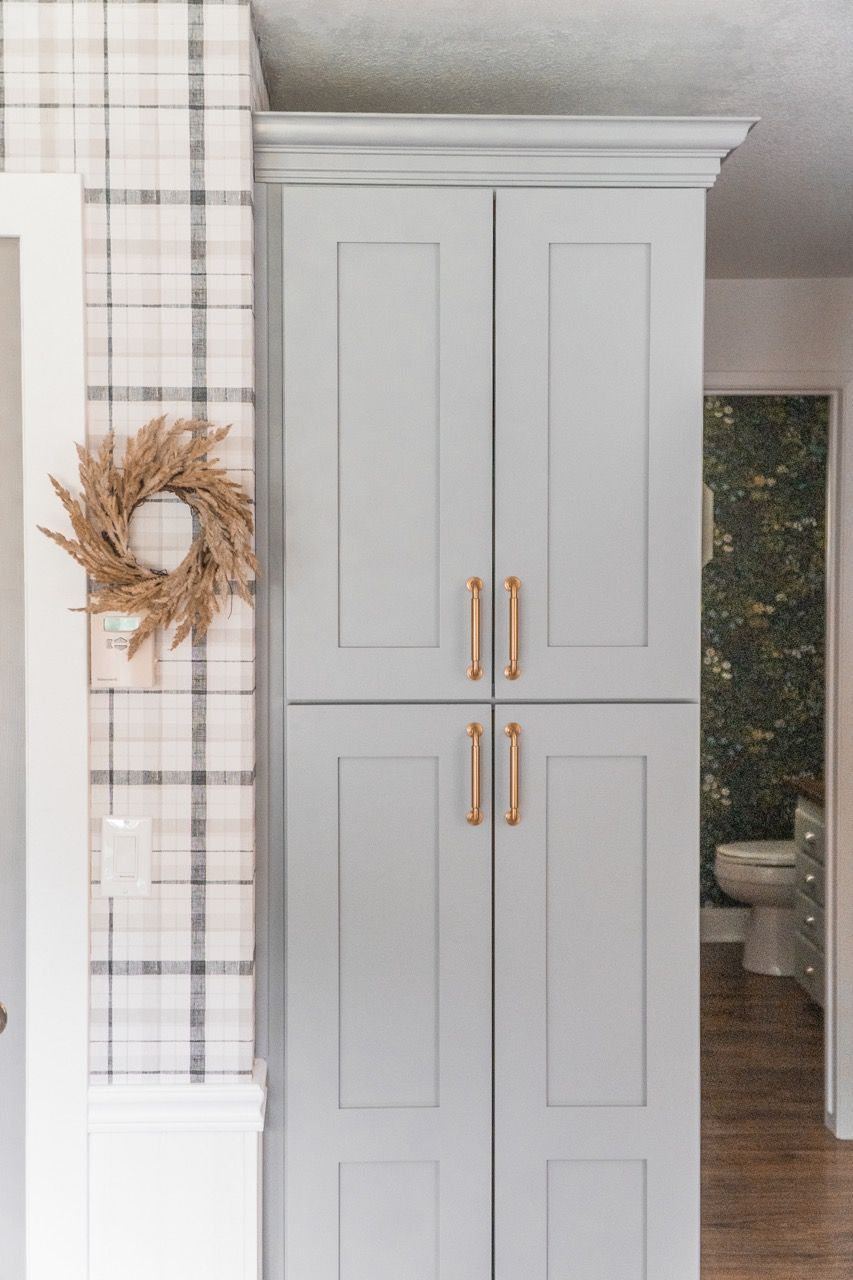 There is a wreath hanging on the wall next to a cabinet.