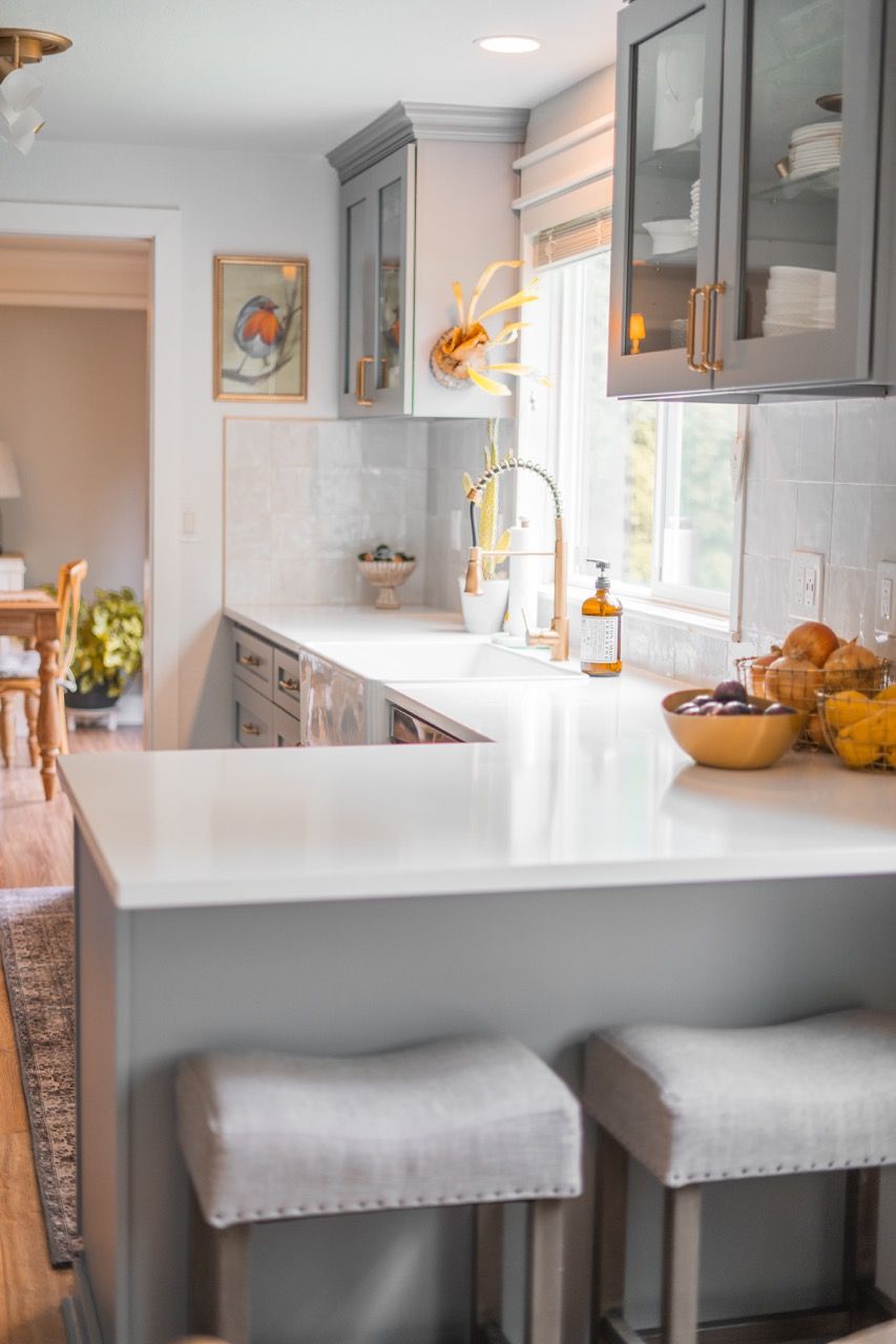 A kitchen with a sink , counter tops , cabinets and stools.