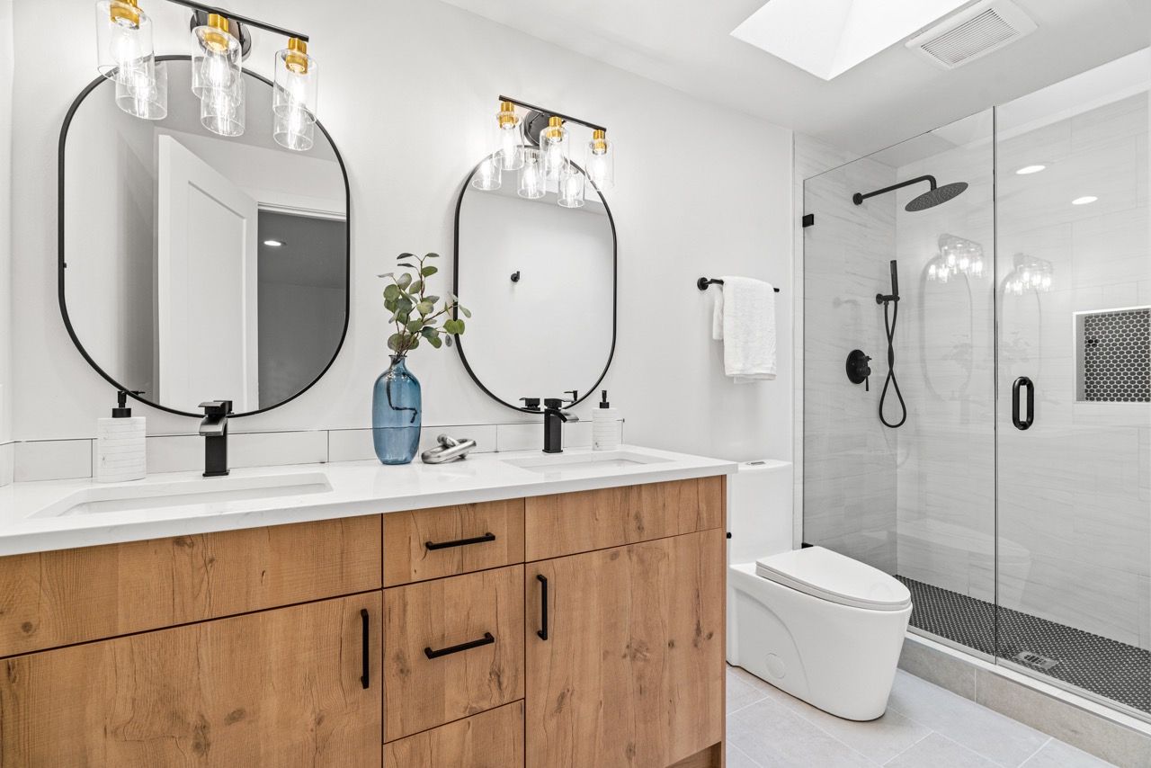 A bathroom with two sinks , a toilet , and a walk in shower.