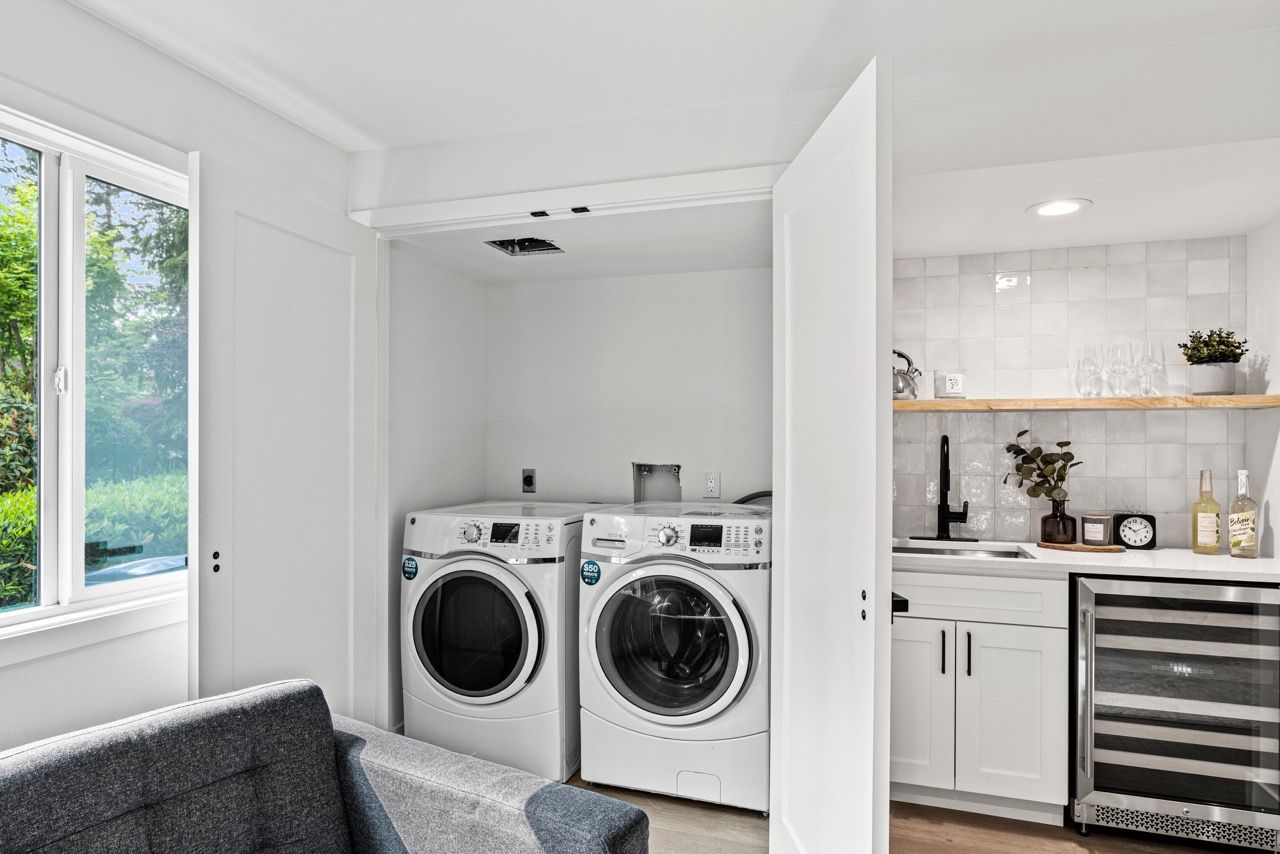 A laundry room with a washer and dryer and a couch.