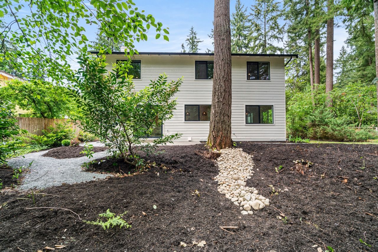 A white house with a lot of windows is surrounded by trees.