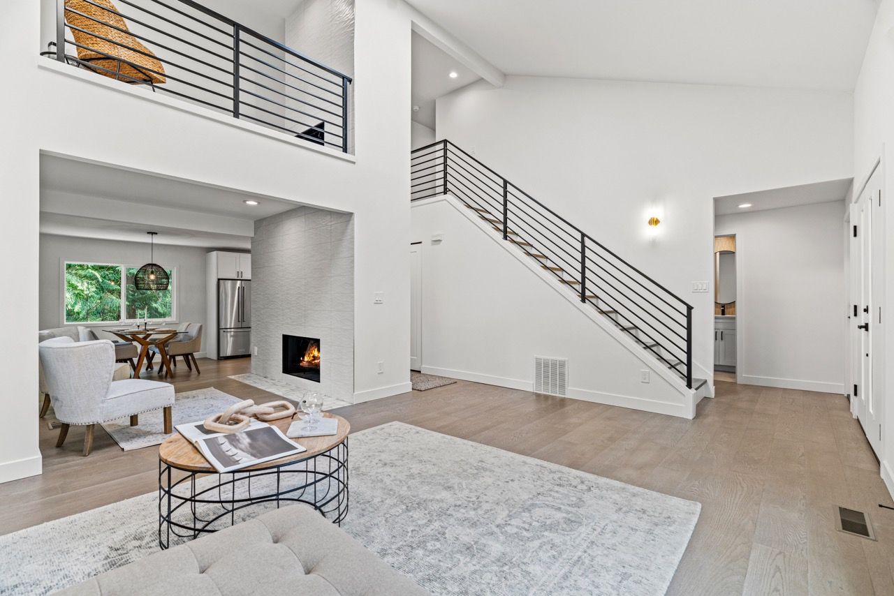 A living room with a fireplace and stairs in a house.