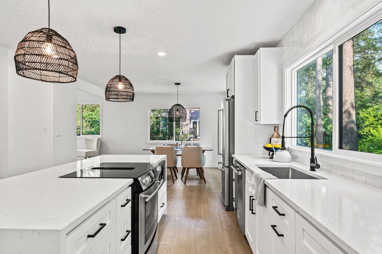 A kitchen with white cabinets , stainless steel appliances , a sink and a stove.