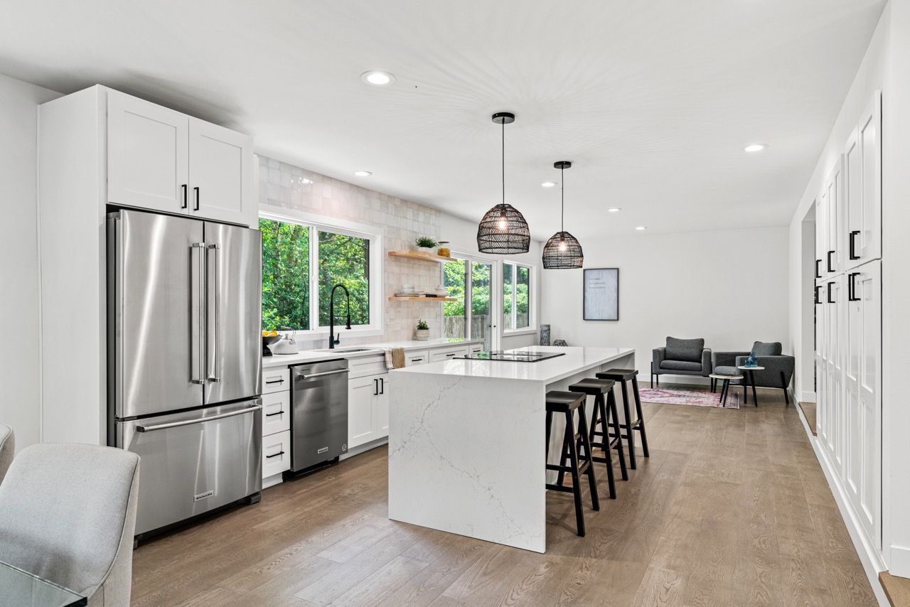 A kitchen with white cabinets and stainless steel appliances and a large island.