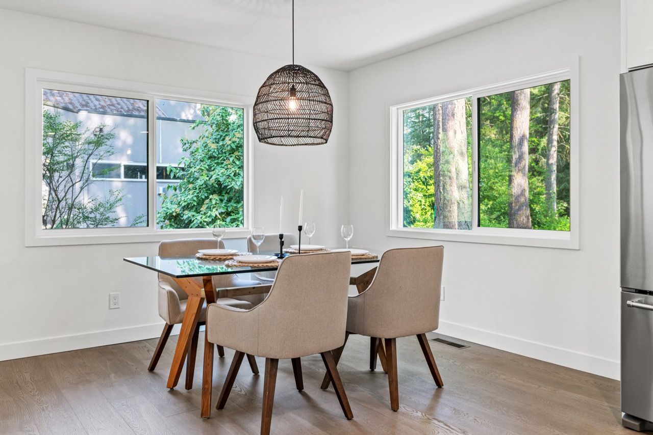 A dining room with a table and chairs and a refrigerator.