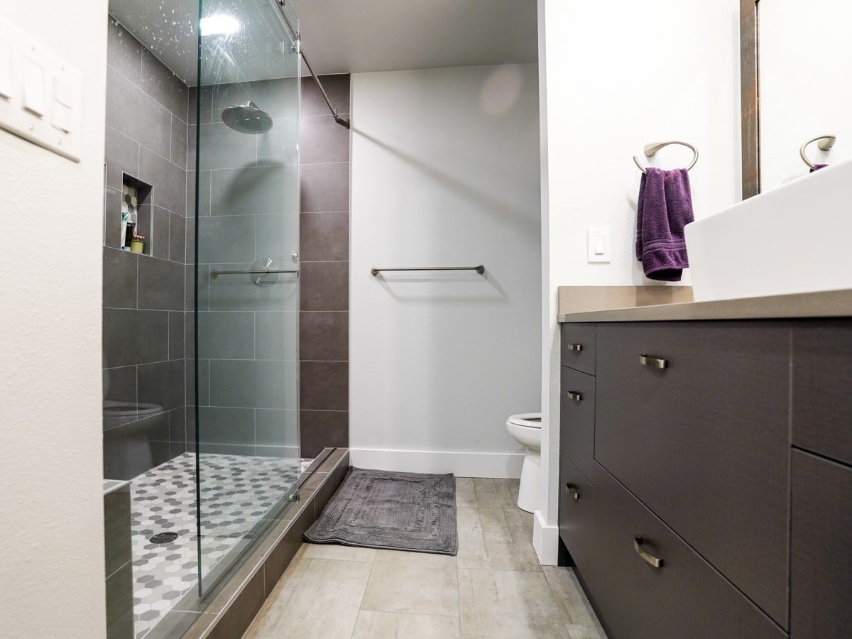 A bathroom with a walk in shower , sink and toilet.