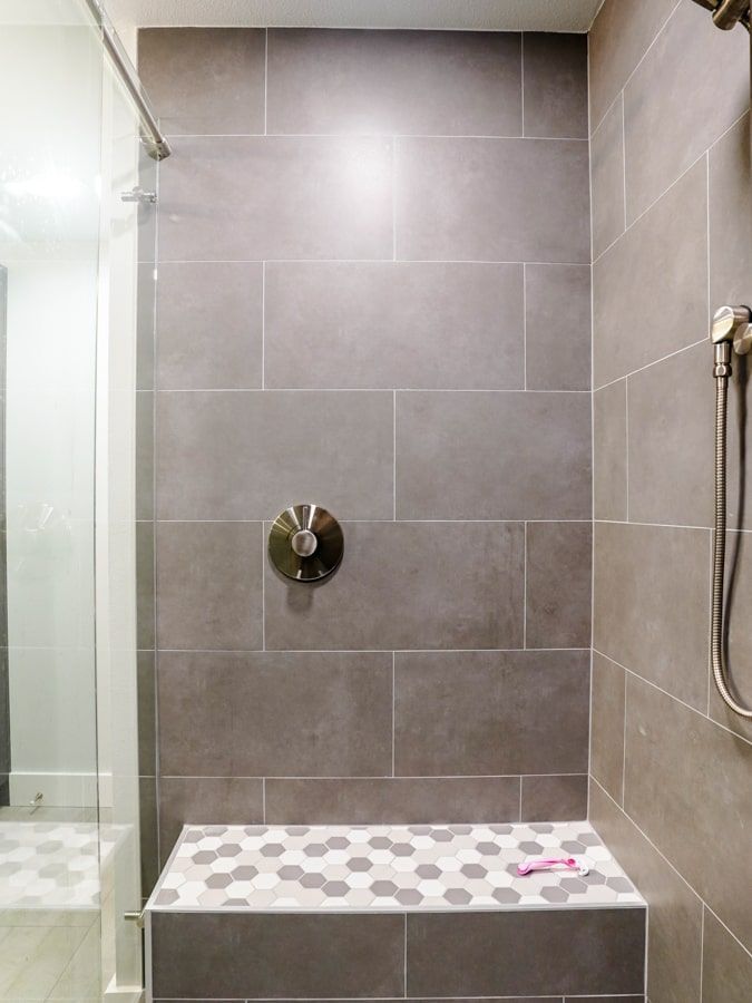 A bathroom with a walk in shower and a bench.