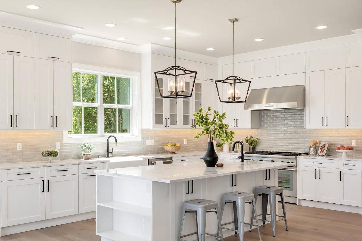 A kitchen with white cabinets , stainless steel appliances , and a large island.