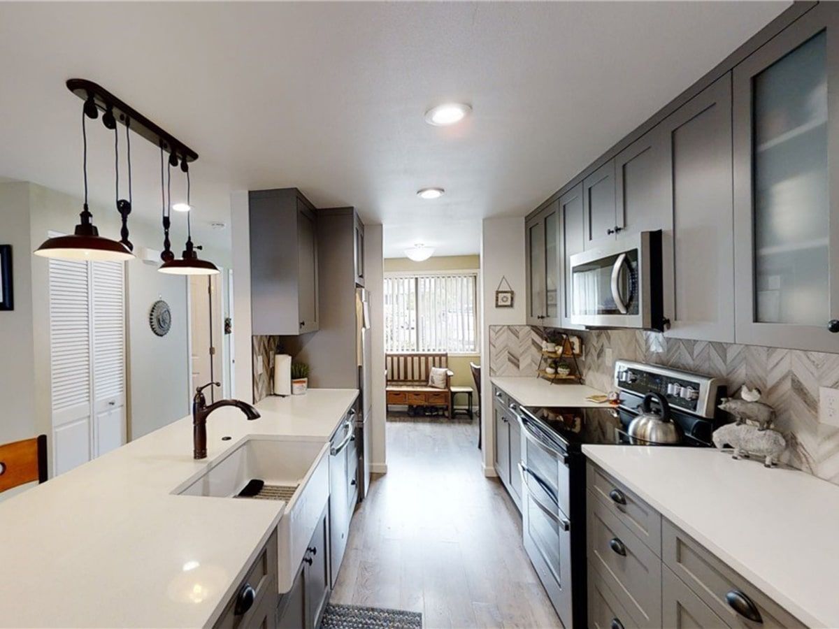 A kitchen with gray cabinets and white counter tops