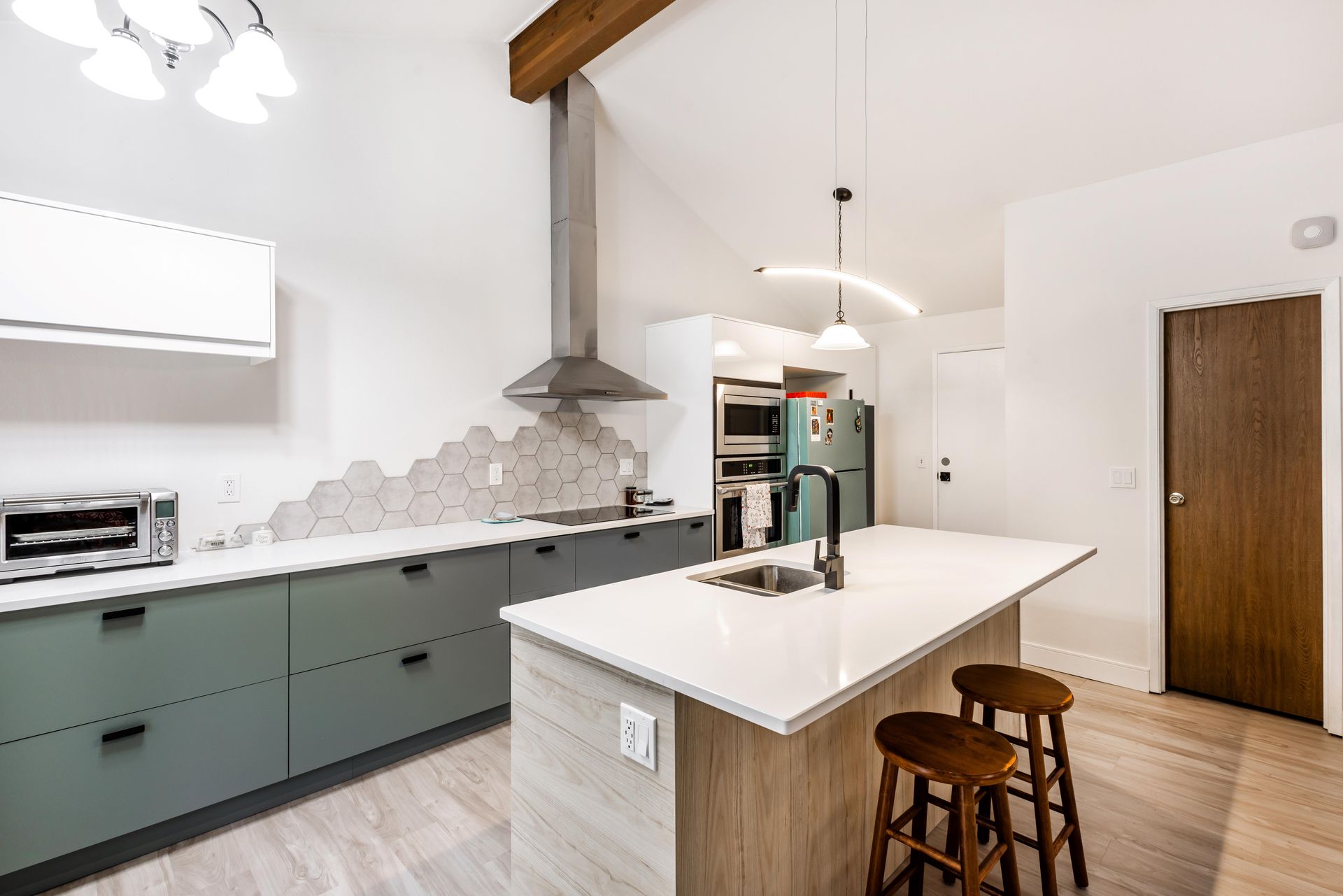 A kitchen with a large island and stools in it.