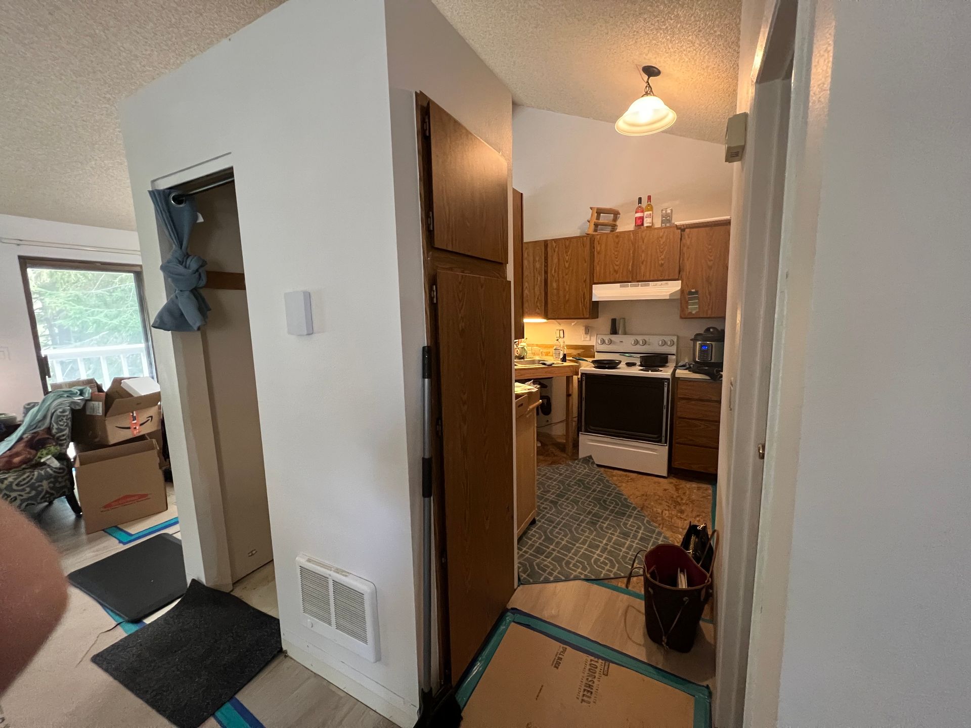 A person is standing in a hallway leading to a kitchen.