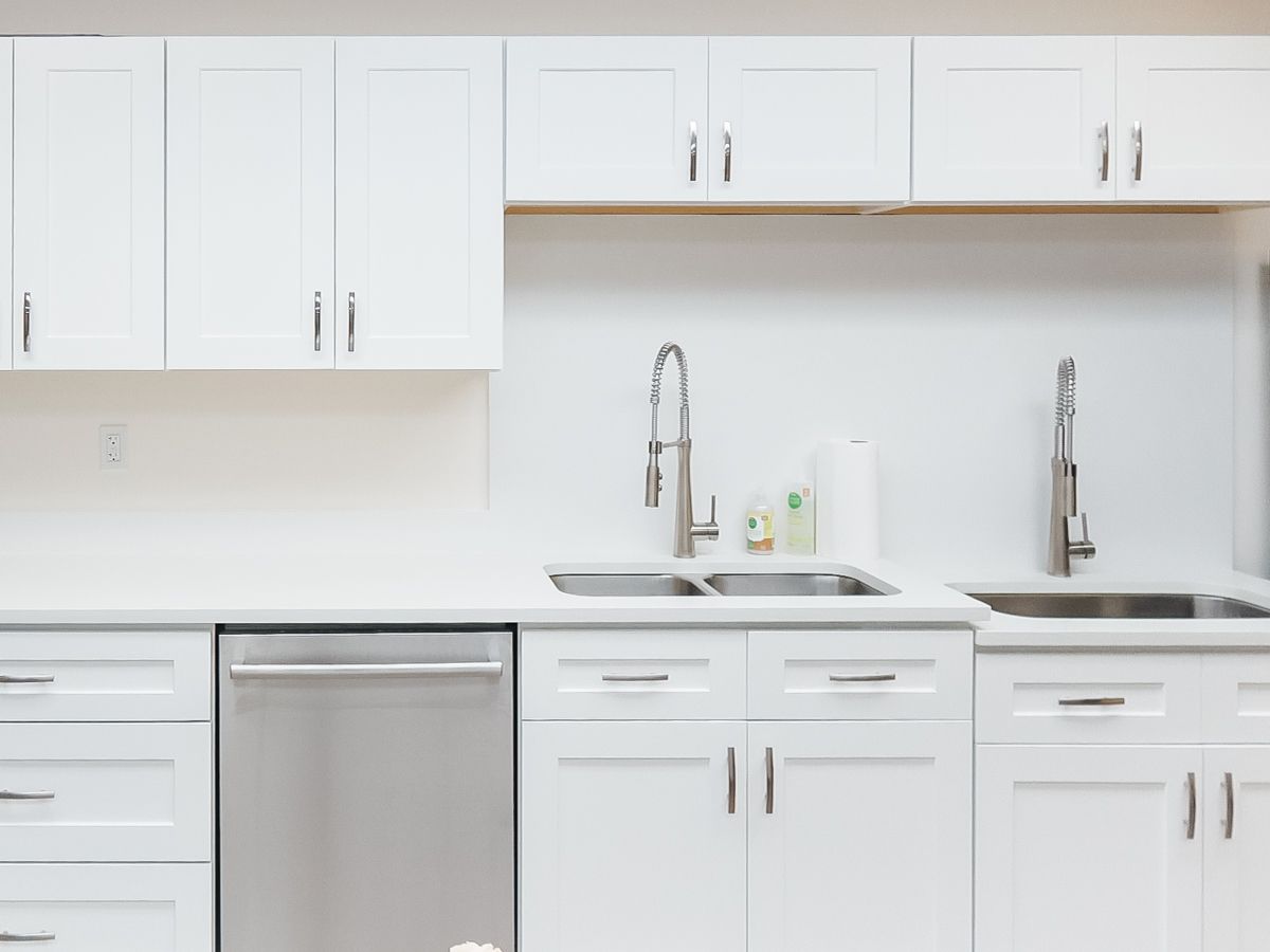 A kitchen with white cabinets , stainless steel appliances , a sink , and a dishwasher.