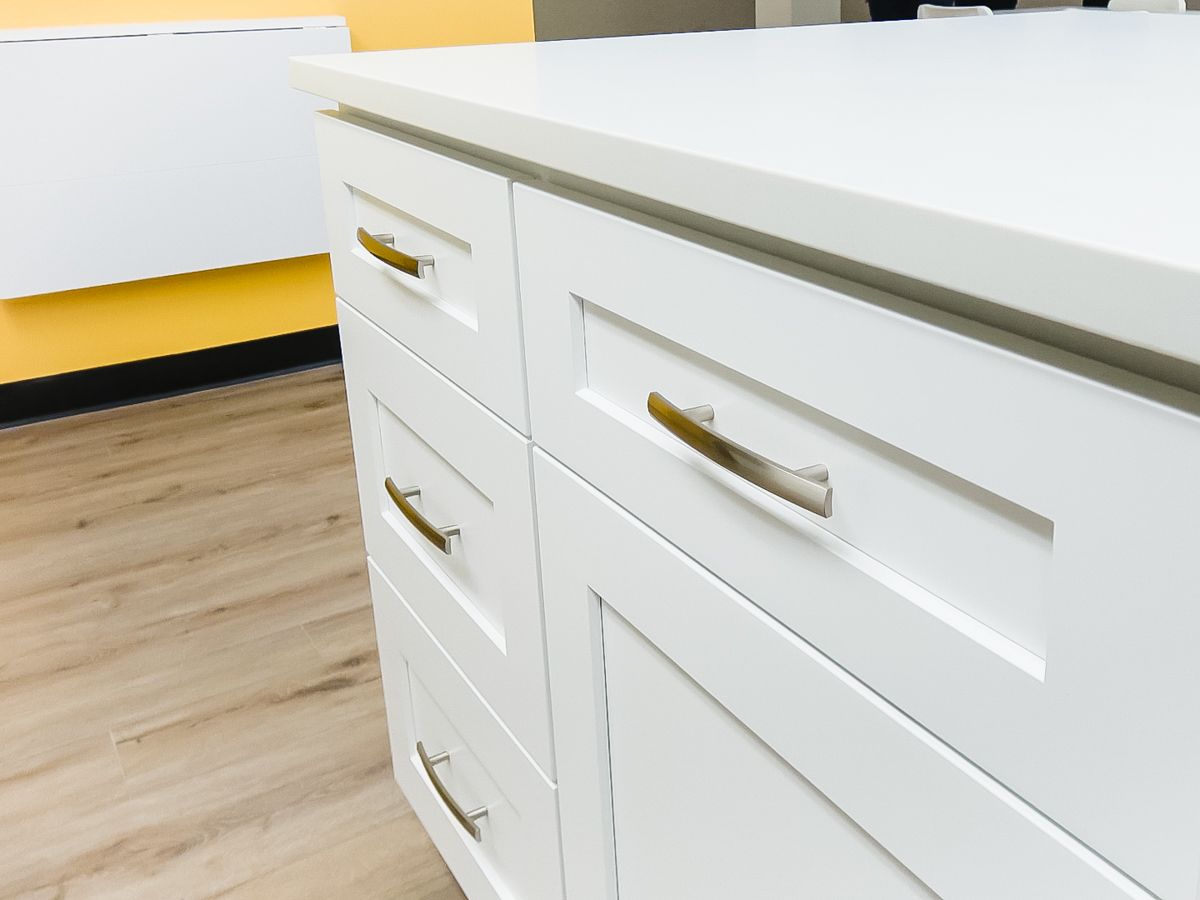 A close up of a white cabinet with gold handles