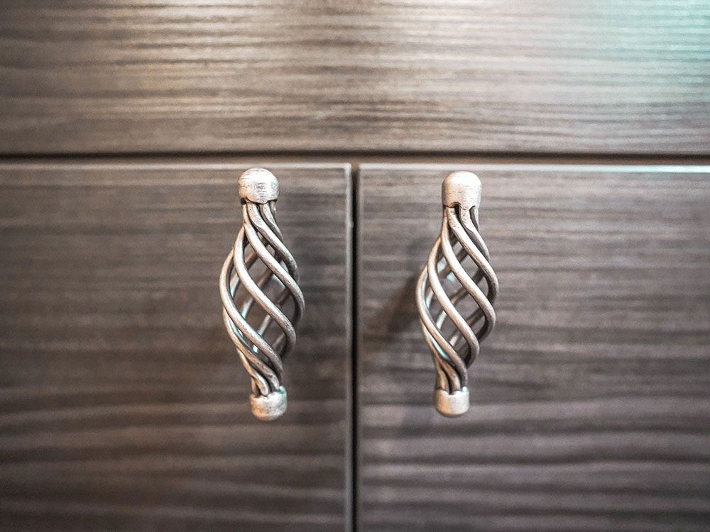 A close up of a pair of cabinet handles on a wooden cabinet.