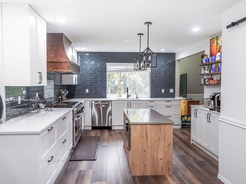 A kitchen with white cabinets , stainless steel appliances , and a large island.
