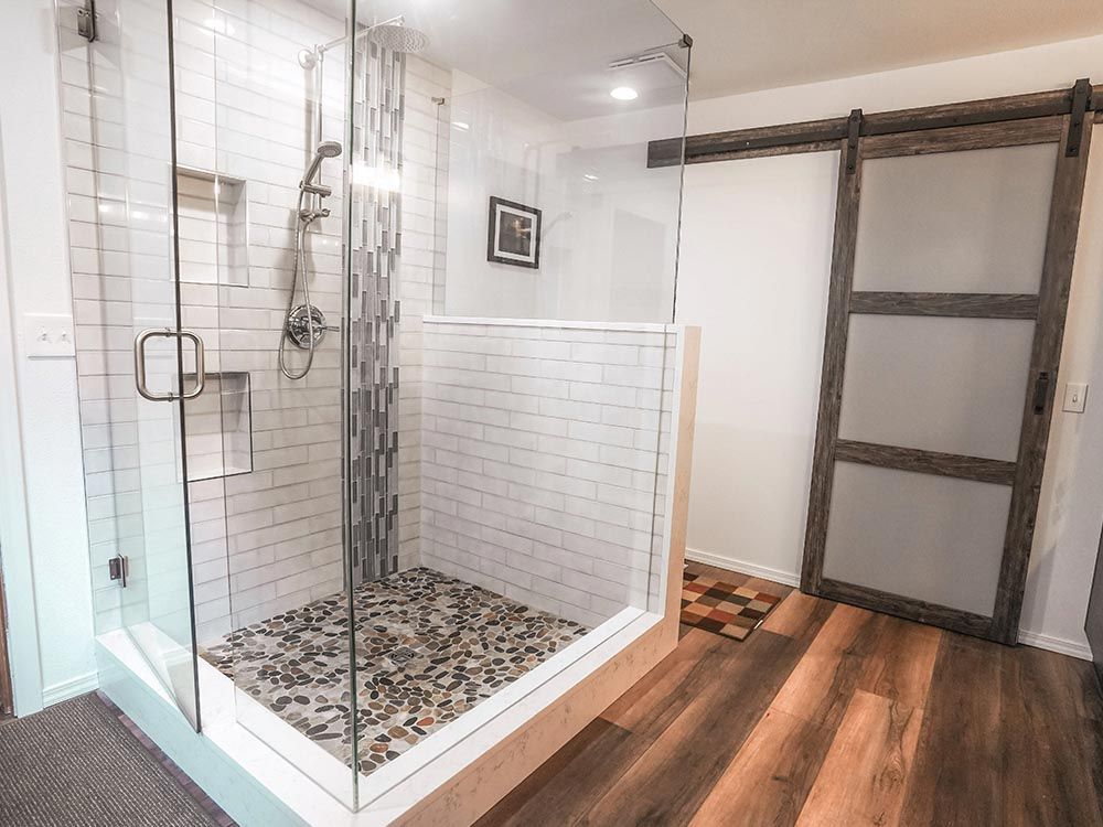 A bathroom with a walk in shower and a sliding barn door.