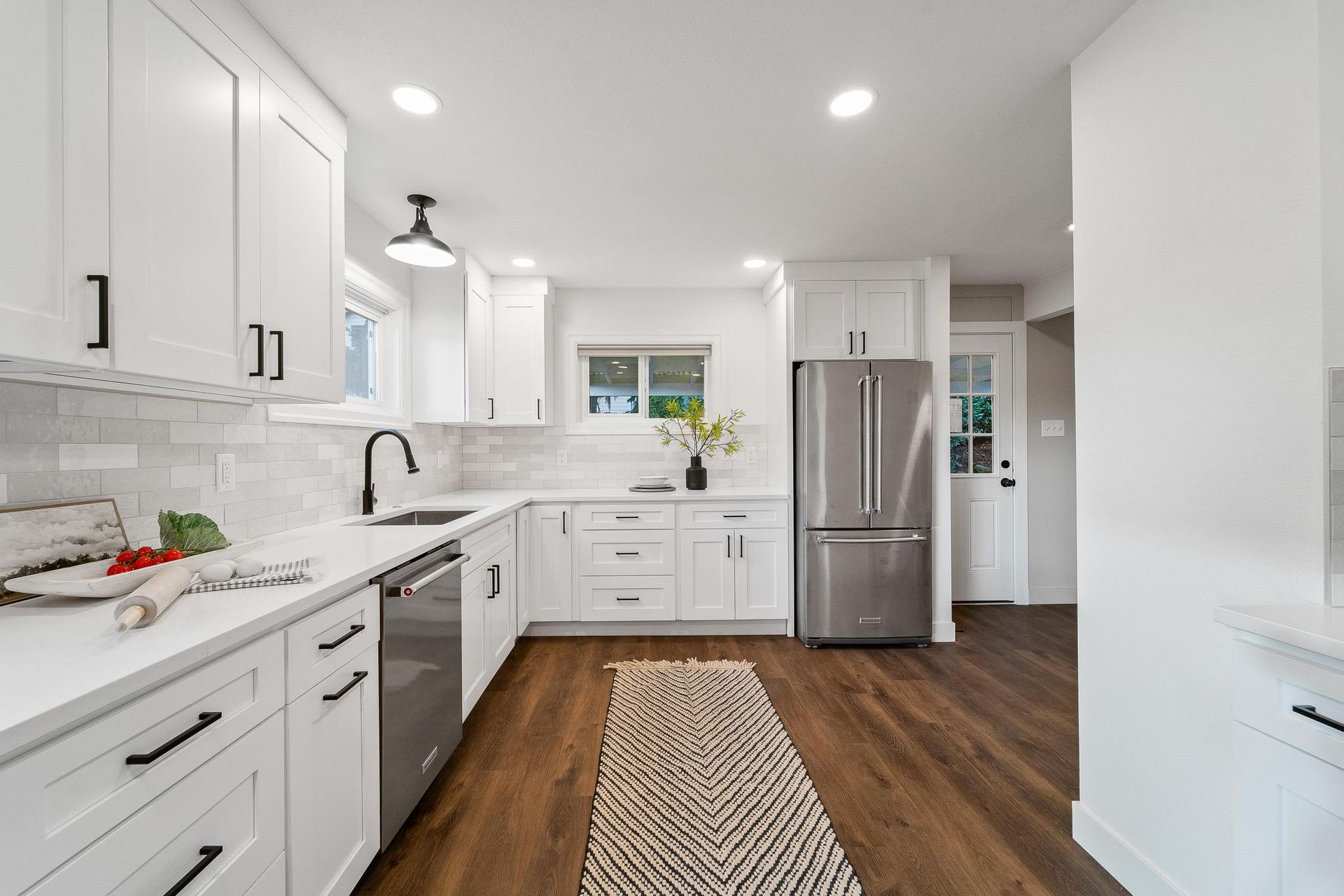 A kitchen with white cabinets , stainless steel appliances , and hardwood floors.