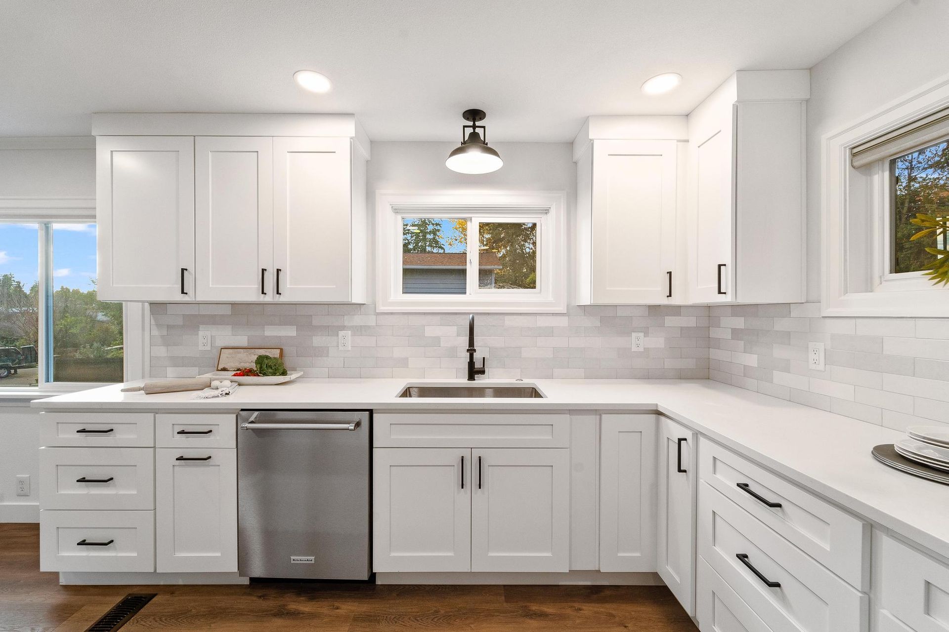A kitchen with white cabinets , stainless steel appliances , a sink , and a window.