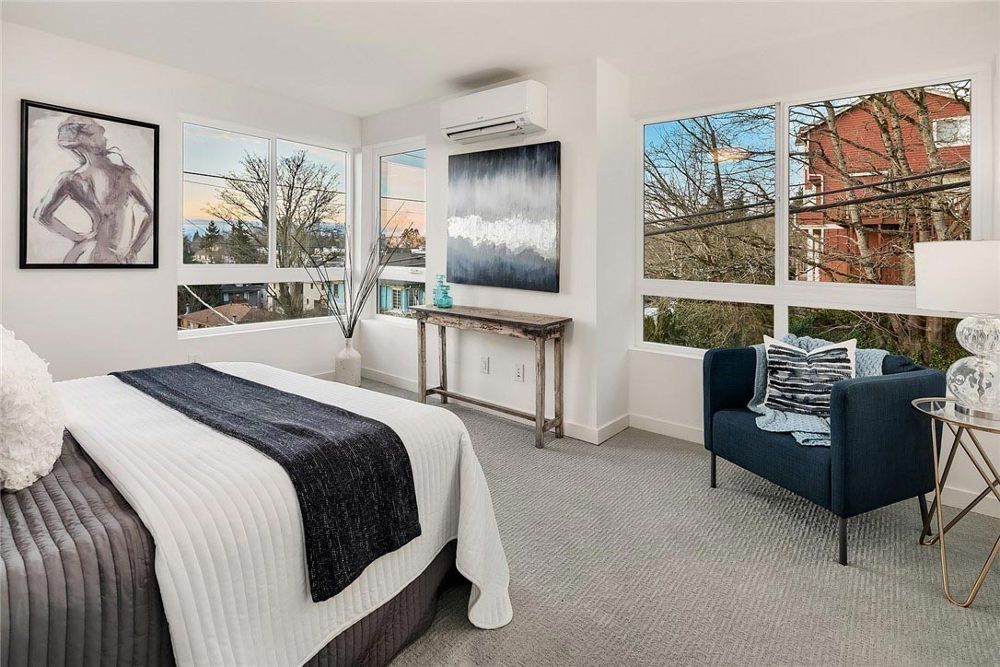 A bedroom with a bed , chair , table and windows.