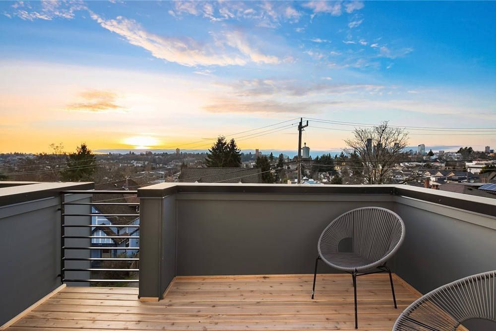 A balcony with a chair and a table with a view of the city at sunset.