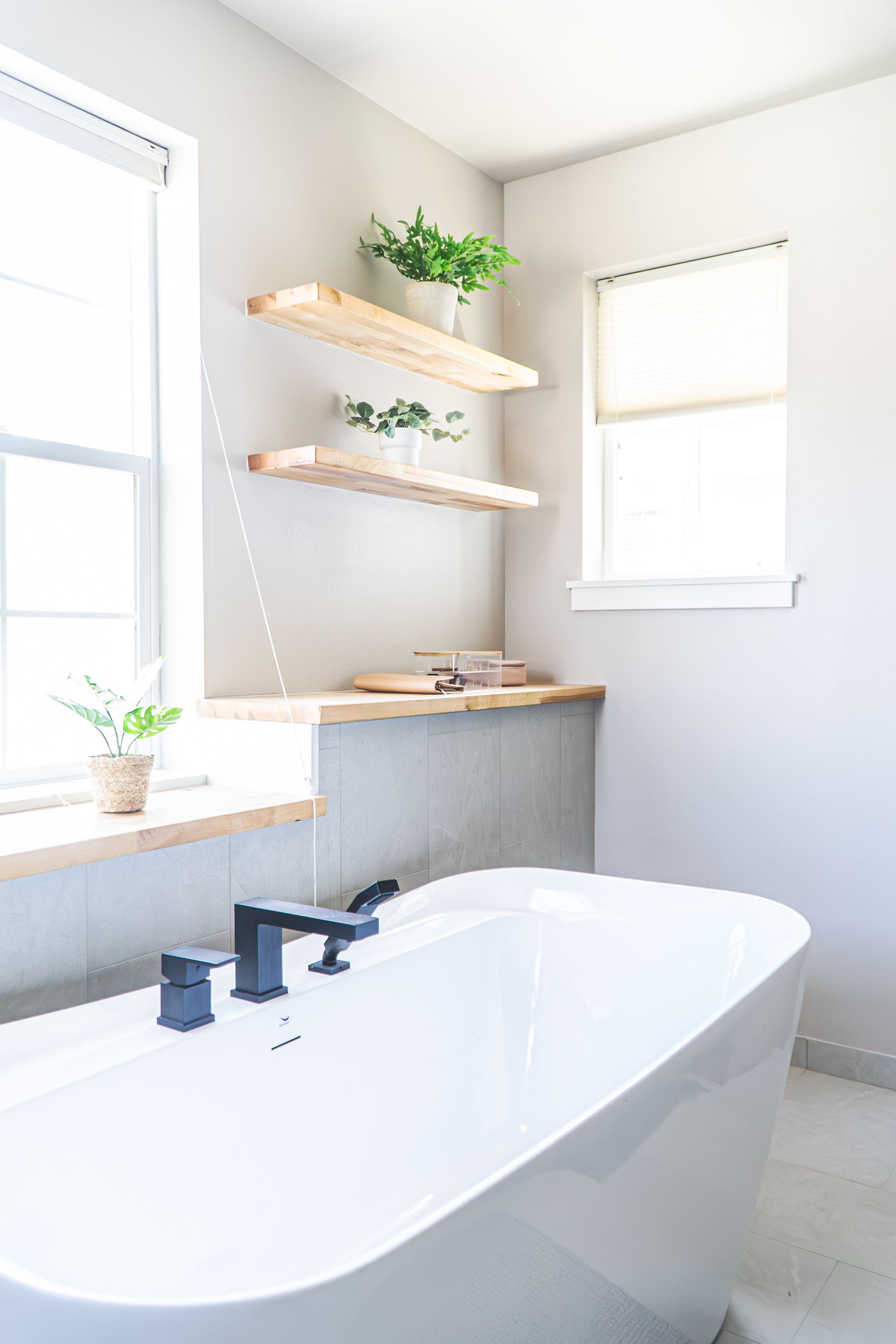 There is a bathtub in the bathroom next to a window.