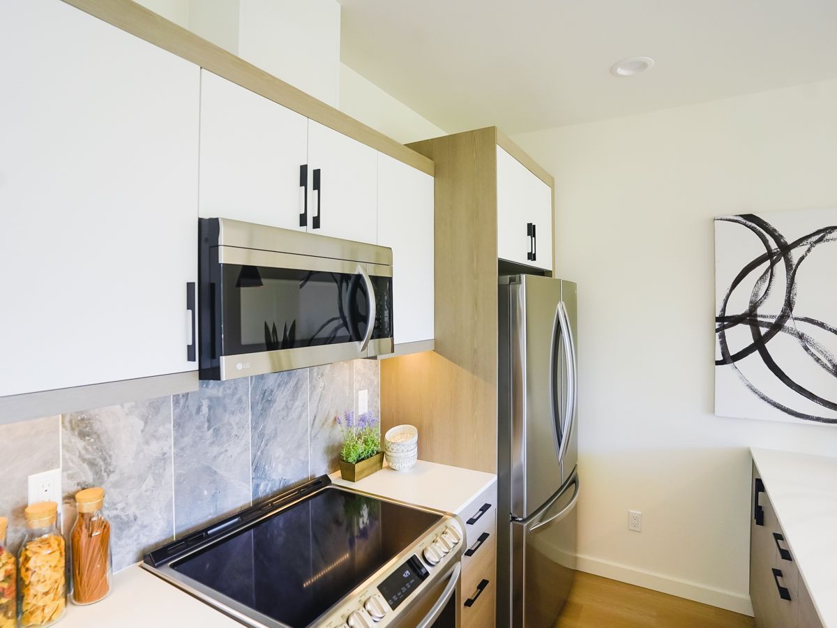 A kitchen with a stove top oven , microwave , refrigerator and stainless steel appliances.