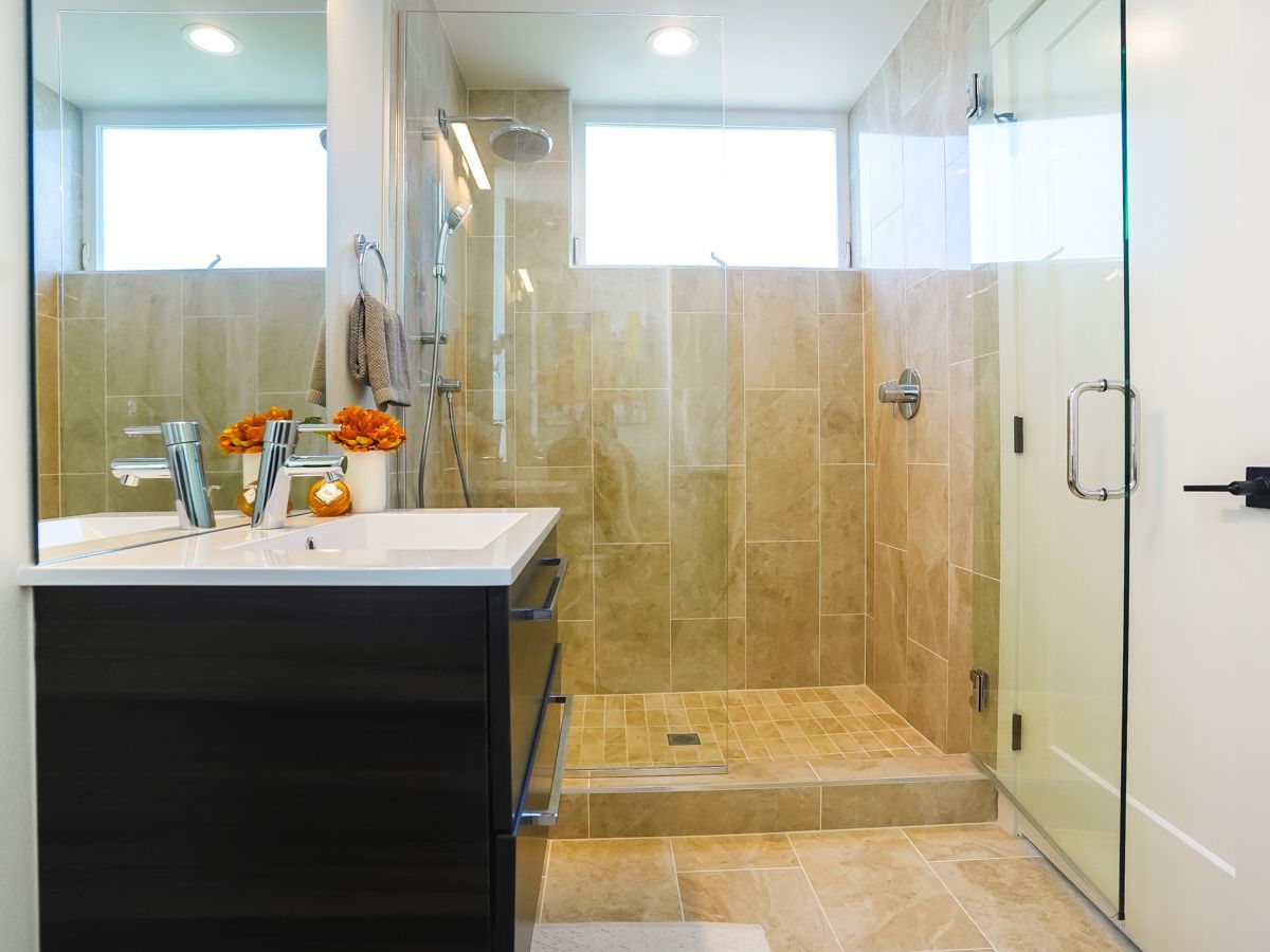 A bathroom with a walk in shower and a sink.