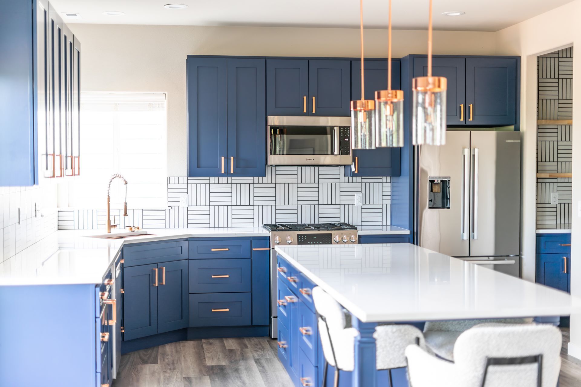 A kitchen with blue cabinets , white counter tops , stainless steel appliances and a large island.