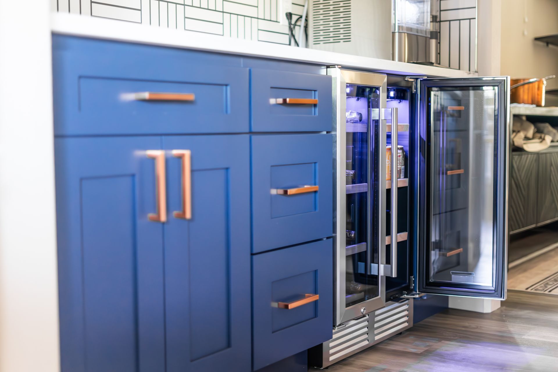 A kitchen with blue cabinets and a stainless steel refrigerator.