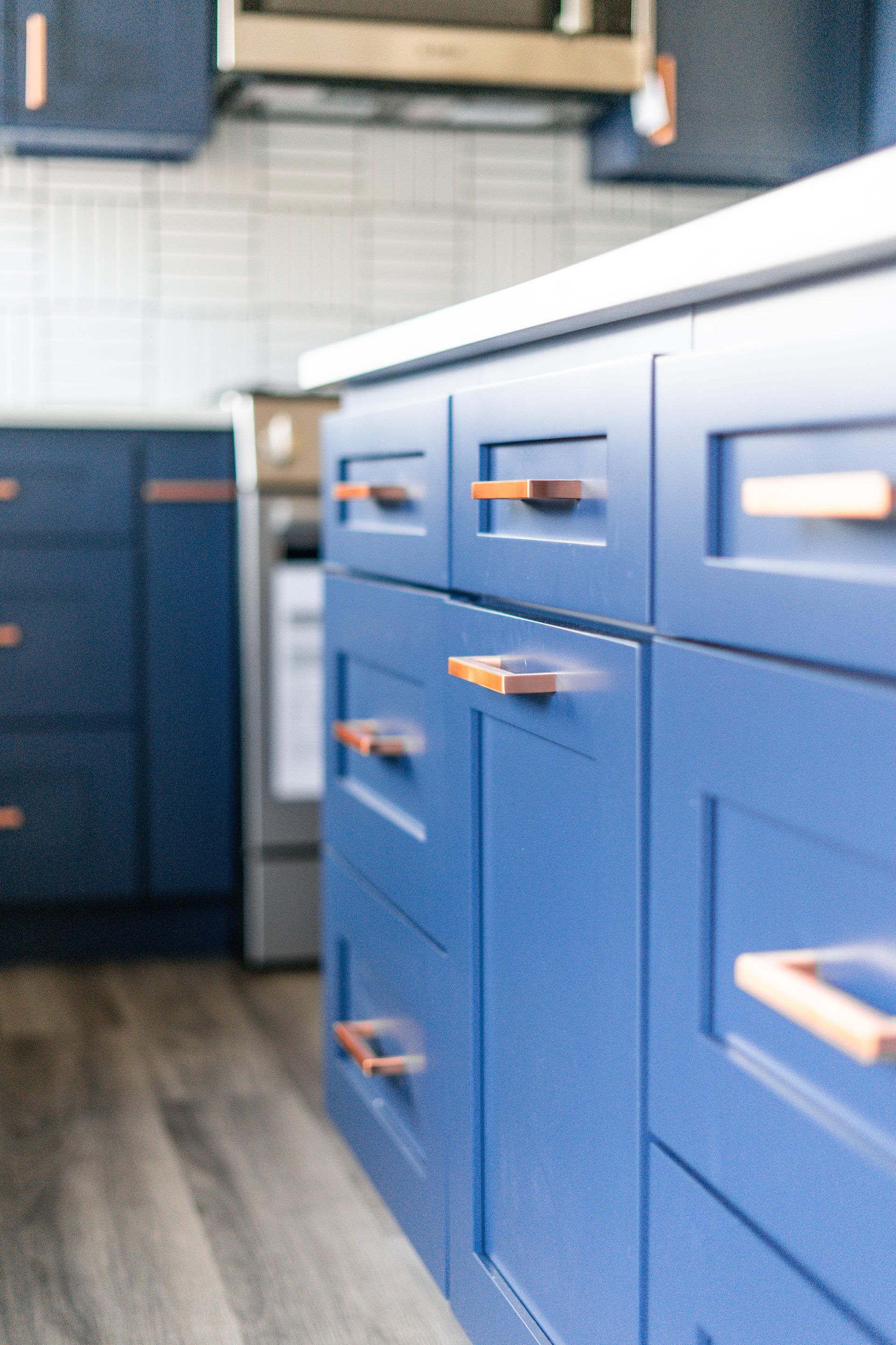 A kitchen with blue cabinets and copper handles.