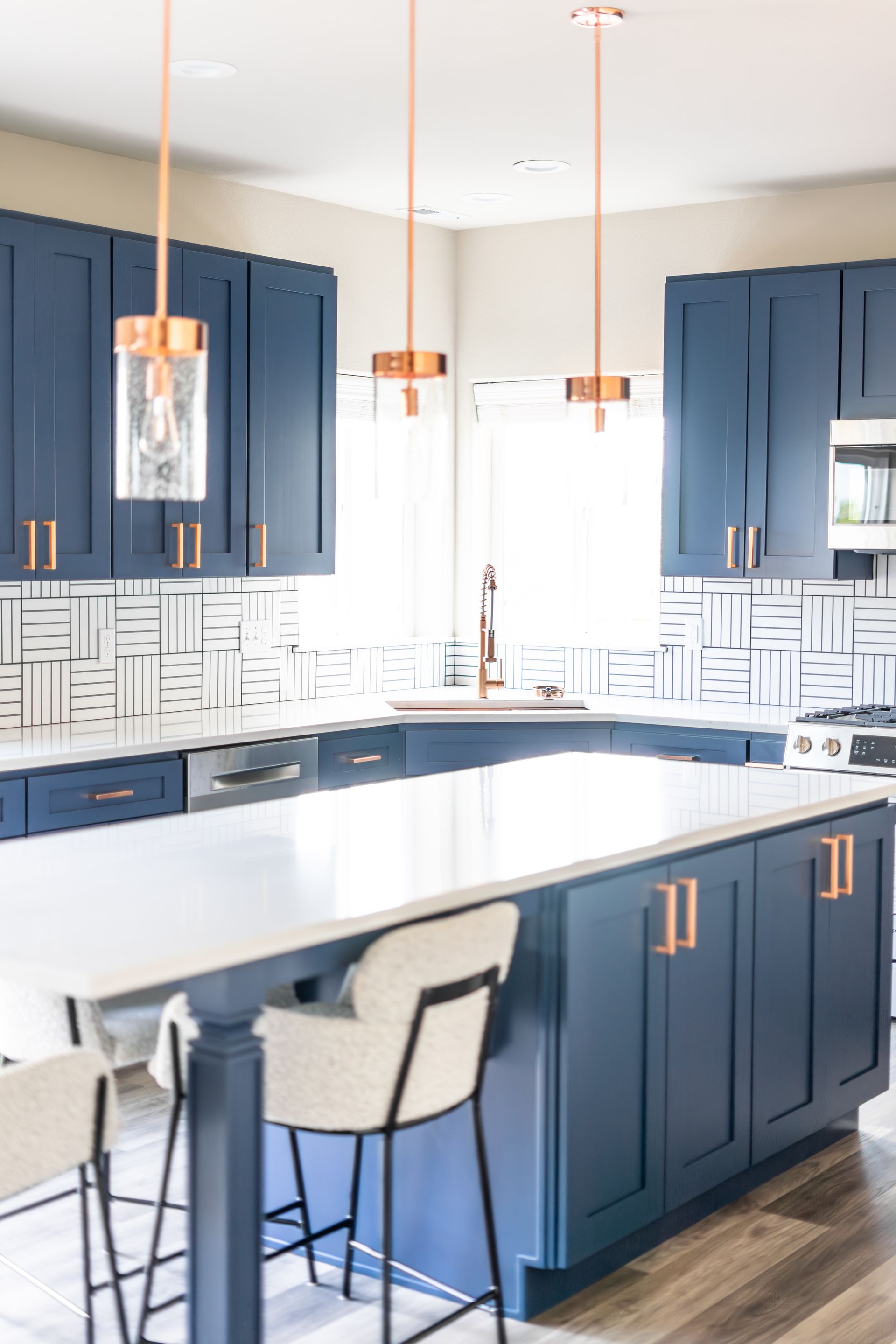 A kitchen with blue cabinets , white counter tops , and a large island.