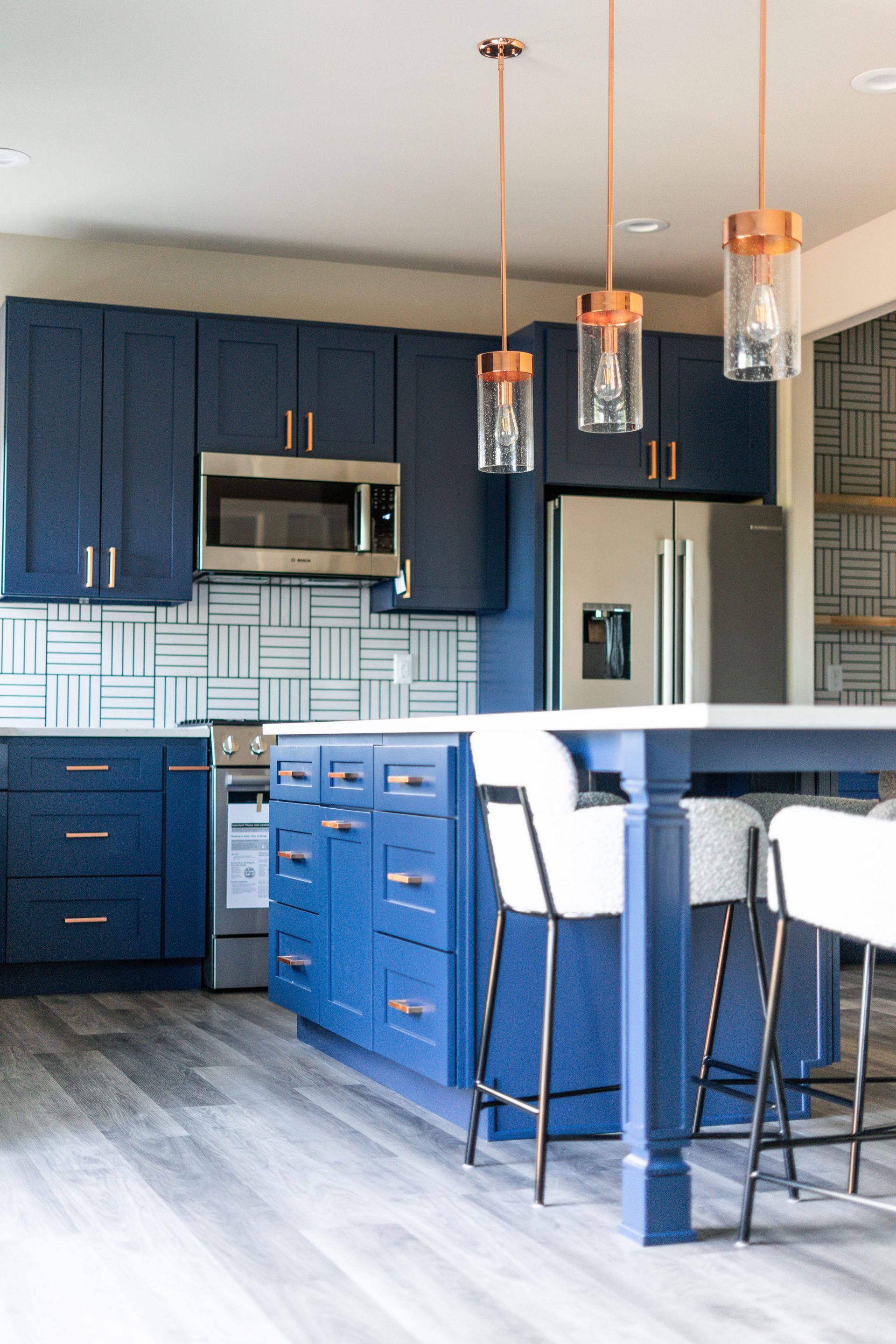 A kitchen with blue cabinets and white stools