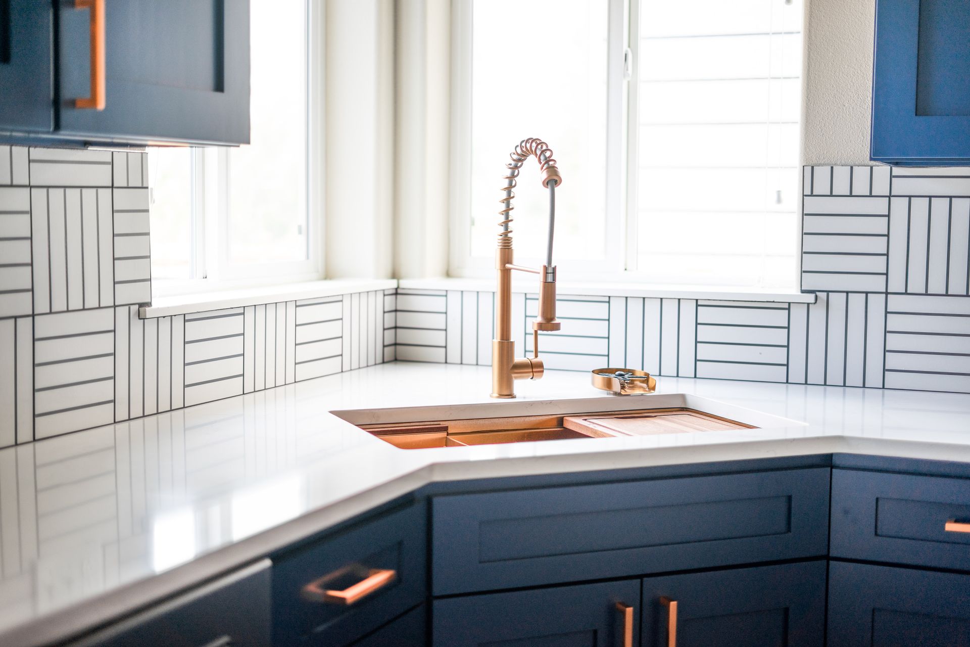 A kitchen with blue cabinets and a sink with a copper faucet.