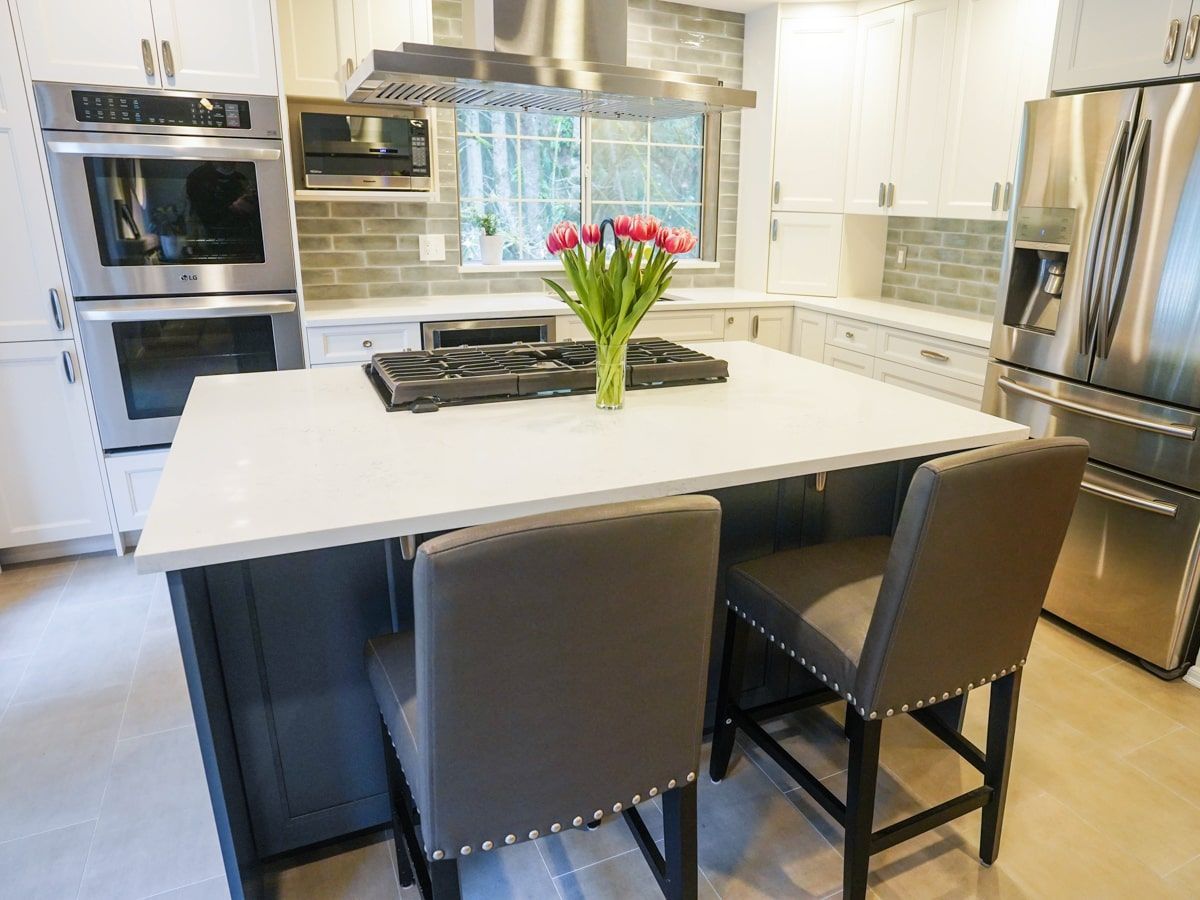 A kitchen with stainless steel appliances and a large island with a vase of flowers on it.