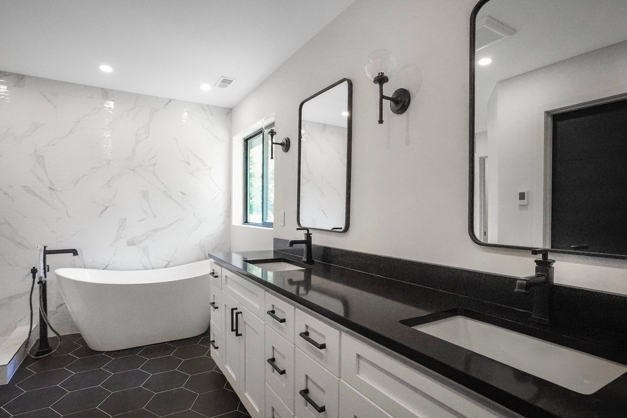 A bathroom with two sinks , a bathtub , and two mirrors.