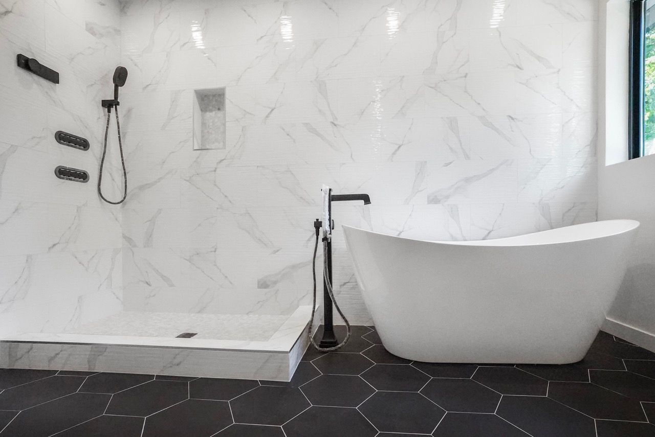 A bathroom with a tub , shower , and window.