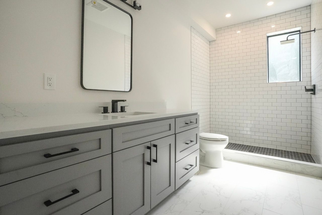 A bathroom with a toilet , sink , mirror and shower.