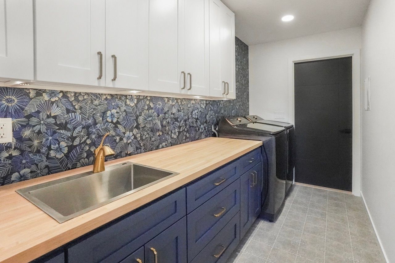 A kitchen with blue cabinets , a sink , and a washer and dryer.